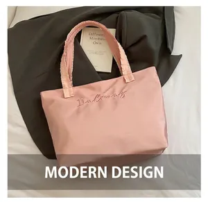 Close-up of pink tote bag with ruffle handles and I am Creamy embroidery on silk fabric