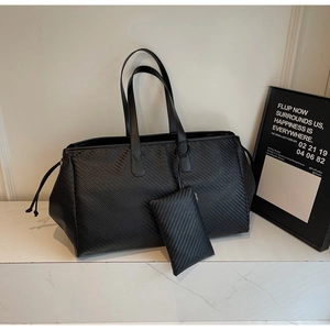 Détail du sac cabas noir tissé avec pochette zippée assortie sur fond de marbre