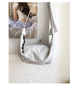 Detail of light grey pleated dumpling bag with decorative knotted wide shoulder strap
