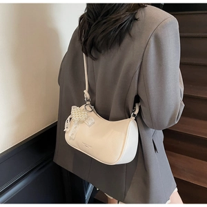 Dettaglio borsa hobo bianco crema con ciondolo a cuore di perle e fiocco di pizzo