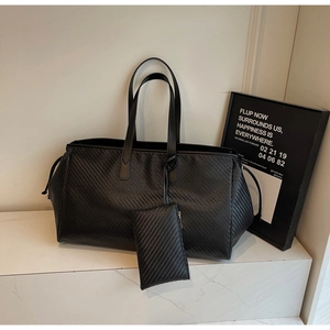 Détail du grand sac cabas noir tressé avec pochette assortie sur marches en marbre