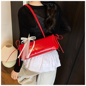 Detail of red leather shoulder bag featuring white lace-up ribbons and side bow accents