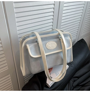 Détail du sac JK bleu clair avec passepoil blanc contrasté et emblème de marque