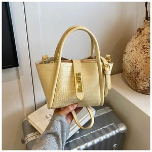 Detail of light yellow bucket bag with crocodile pattern and golden metal clasp