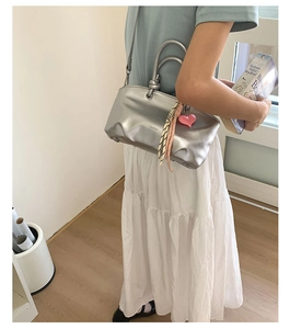 Detail of silver bucket bag with ring handle and decorative pink heart charm accessory