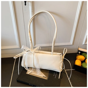 Detail view of cream rectangle shoulder bag with lace bow and drawstring side ties