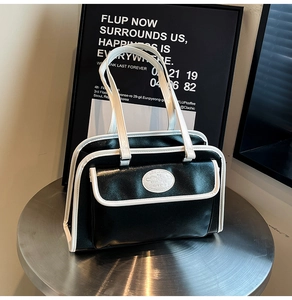Détail du sac à bandoulière en cuir noir et blanc contrasté avec poche frontale pratique