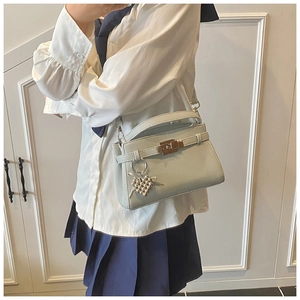 Detail of light green mini handbag with heart charm and golden metal hardware lock