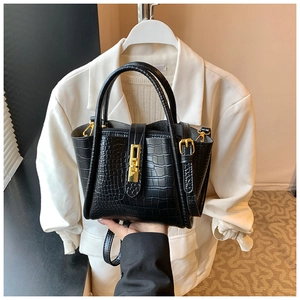 Detail of black crocodile texture bag with elegant gold twist lock and handle