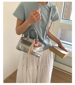 Detail of silver metallic PU tote with double knot handles and pink heart charm