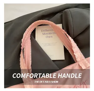 Detail of pink tote bag showing ruffled handle edges and elegant tone-on-tone embroidery