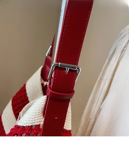 Détail de la bandoulière en cuir rouge réglable avec boucle argentée sur le sac