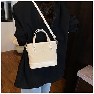 Model view of cream bucket bag with canvas leather patchwork and metal logo detail