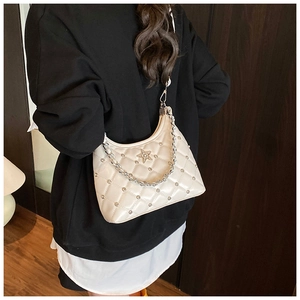 Détail d'un sac sous le bras crème matelassé avec étoile argentée et clous sur chaîne