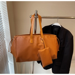 Détail du sac cabas tressé avec pochette assortie et cordon de serrage en cuir orange