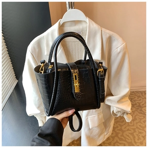 Close-up of black crocodile-embossed leather bucket bag with gold metal twist lock detail