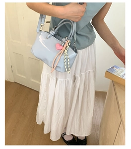 Close-up of light blue patent leather bucket bag with heart charm on a female model