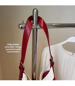 Détail de la bandoulière réglable en cuir rouge sur un sac tissé avec boucle en métal