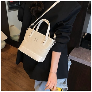 Fashionable beige bucket bag detail featuring lychee texture and metallic silver logo