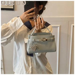 Detail of light blue lychee pattern leather bag with metal lock and heart charm