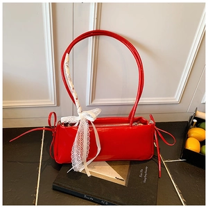 Detail of red patent leather shoulder bag with white lace ribbons and silk scarf accents