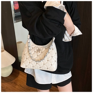 Détail du sac matelassé blanc avec emblème étoile argenté et bandoulière en chaîne