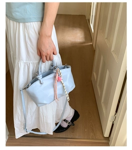 Close-up of a light blue textured PU bucket bag with woven handle and heart charm