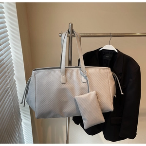 Vue détaillée du sac cabas tissé avec pochette assortie sur un cintre en métal