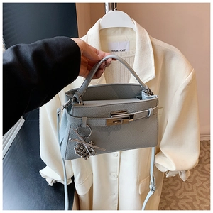 Detail of greyish blue lychee pattern leather bag with silver metal lock and ball pendant