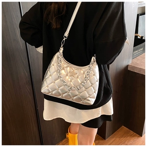 Silver quilted crossbody bag with metal star charm and chain strap shown on model