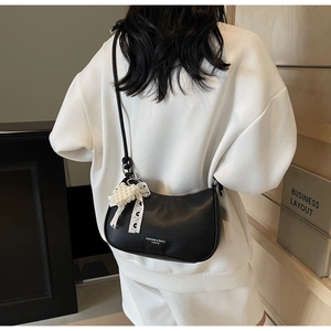 Dettaglio borsa hobo nera in pelle martellata con fiocco in pizzo e ciondolo a perla