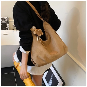 Detail of khaki suede tote bag with brown leather strap and cute bear charm accessory