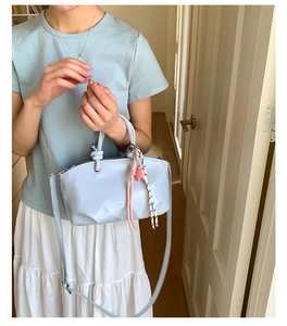 Light blue faux leather bucket bag with braided heart charms and detachable shoulder strap