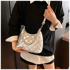 Detail of silver quilted shoulder bag featuring metallic chain and star charm ornament