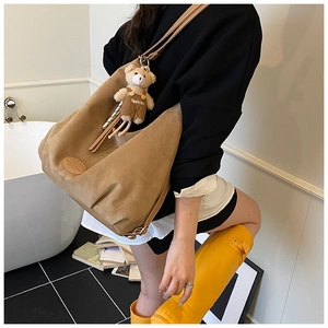 Close-up of large brown suede tote bag with a cute teddy bear charm and leather logo
