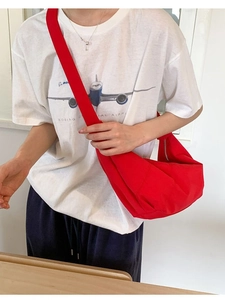 Minimalist red canvas half-moon crossbody bag with wide strap shown on a model