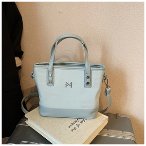 Detail view of the light blue leather bucket bag with silver metal logo and handle