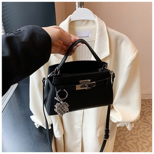 Detail of black lychee grain leather handbag with silver clasp and rhinestone charm