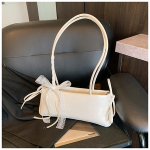 Close-up of cream underarm bag featuring a delicate lace bow and smooth leather texture