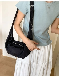 Minimalist black crescent crossbody bag with adjustable wide strap and silver zipper closure
