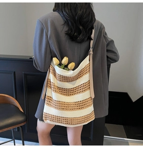 Détail d'un sac cabas tissé à rayures avec bandoulière en cuir porté par un mannequin