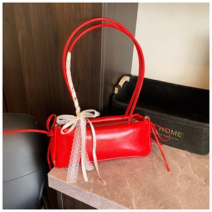 Detail of red oil wax leather shoulder bag with white lace bow and long ribbon accent