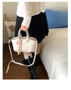 Detail of white bucket bag with heart pendant, silk scarf and adjustable shoulder strap