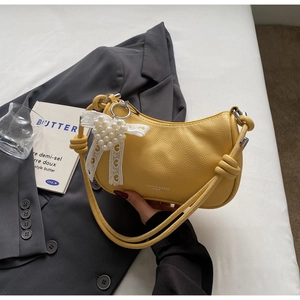 Dettaglio della borsa hobo gialla con trama litchi e ciondolo a cuore di perle