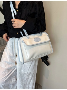 Sac bandoulière rétro crème et bleu clair porté par un mannequin dans un décor épuré