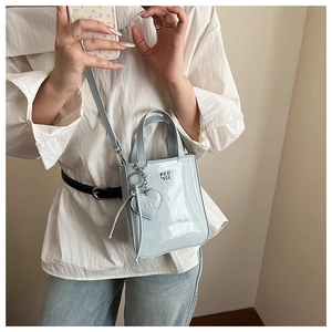 Macro shot of light blue patent leather mini bag with silver heart charm and metal logo