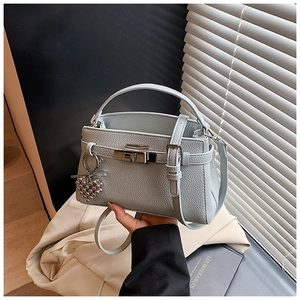 Detail view of light blue lychee pattern leather handbag with heart charm and silver lock