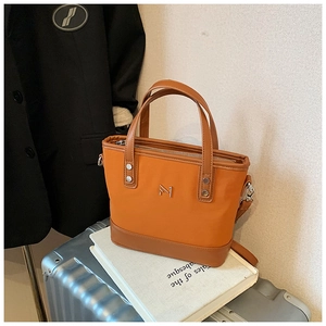 Detail of orange nylon bucket bag with brown leather trim and silver metal M logo