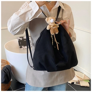 Detail of black canvas tote bag with fashion teddy bear charm and brand logo patch