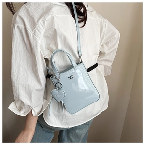 Detail view of light blue patent leather crossbody bag with heart charm and Pan'tor logo